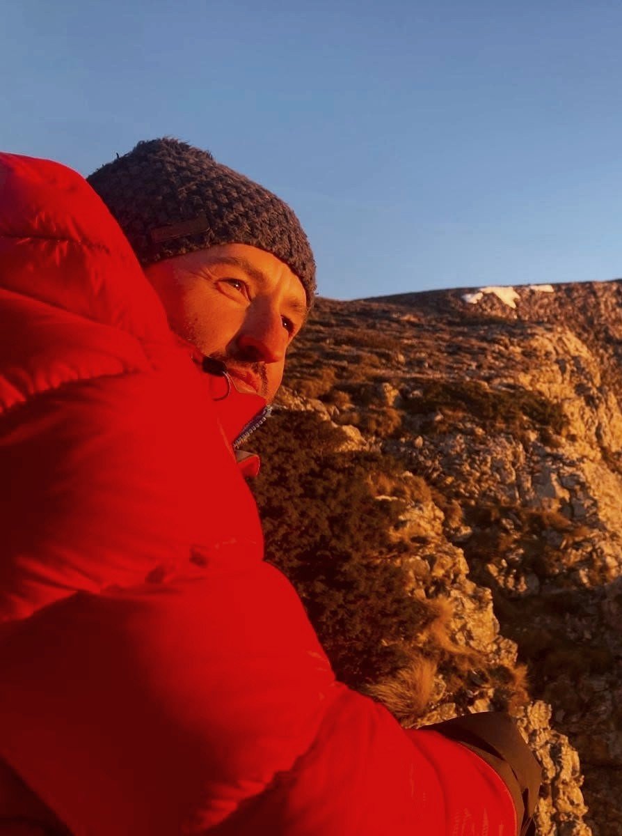 Clément, guide, en doudoune rouge dans la lumière dorée du soir