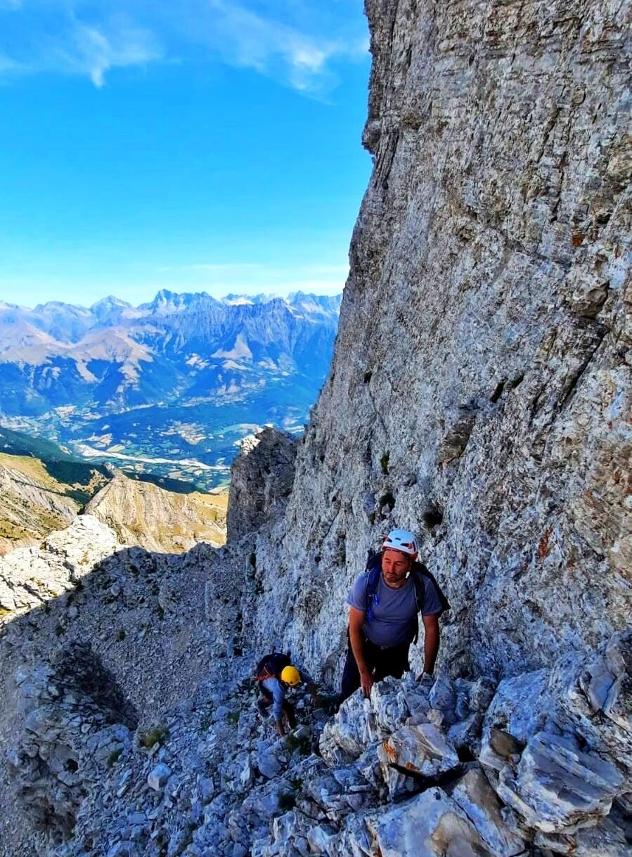 Clément, guide, en escalade sur une falaise calcaire face aux Alpes