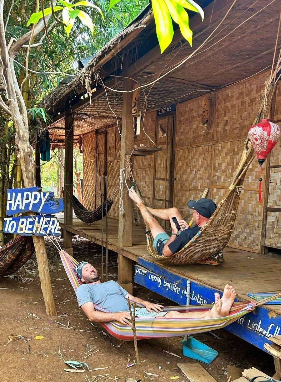 Clément, guide, en hamac devant une cabane en bambou